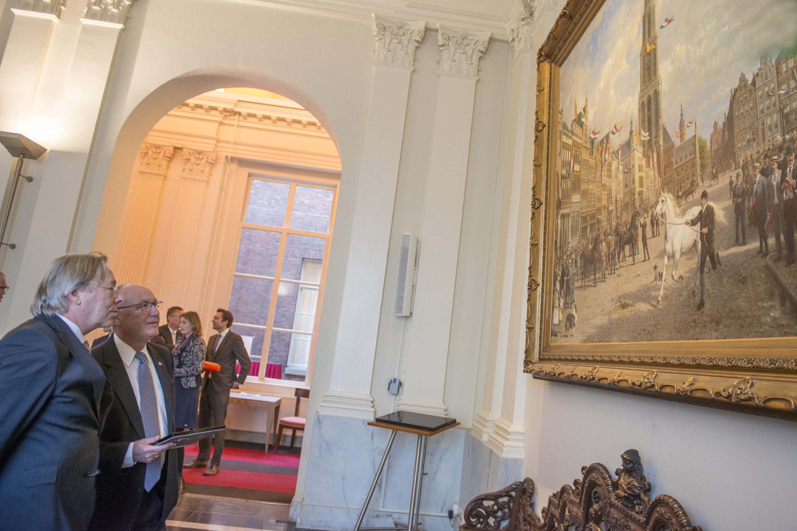 Burgemeester Den Oudsten toont ambassadeur Pete Hoekstra het beroemde schilderij uit 1920 van Otto Eerelman, De Paardenkeuring op de Grote Markt op de 28ste augustus.  