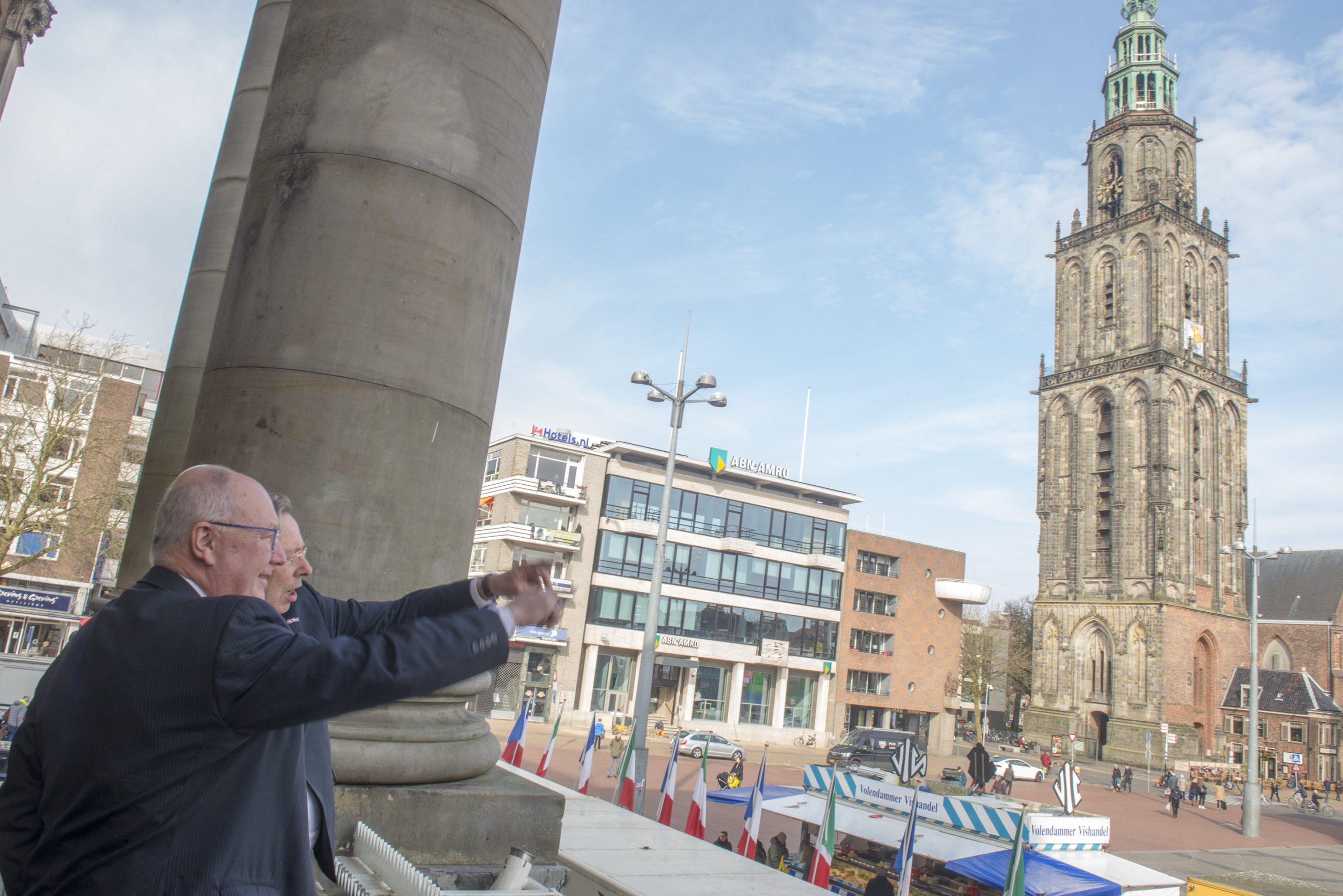 Burgemeester Peter den Oudsten wijst ambassadeur Pete Hoekstra vanaf het bordes van het stadhuis op de voortgang van de bouw van het Groninger Forum.