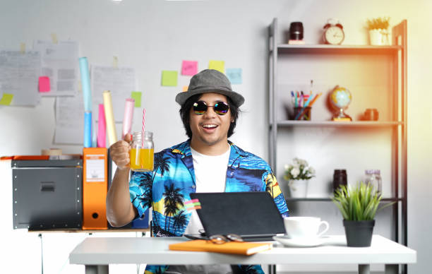 Stylish Young Man Holding Orange Juice While Working on Summer Vacation Season at Office