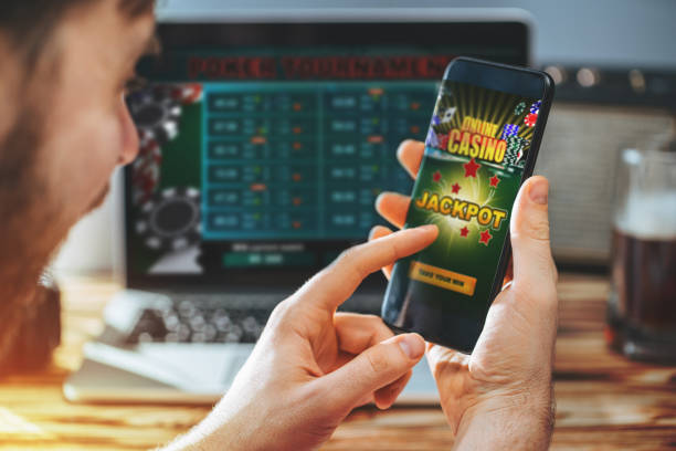 Lucky man celebrating victory after getting jackpot in online casino. Poker tournament on the laptop screen on the background.